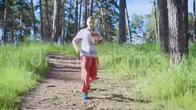 一个成年男子在一个温暖的夏日积极地沿着森林小径奔跑，穿<strong>运动鞋</strong>的人从事<strong>户外</strong>活动